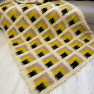 May include: A white, yellow and black geometric patterned throw blanket with a fringed edge.