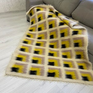 May include: A white, black and yellow geometric patterned throw blanket with a fringed edge.