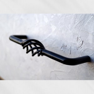 May include: Black metal cabinet door handle with a unique, spring-like design.