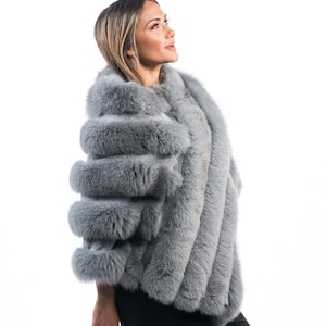 May include: A grey fur poncho with a long, flowing design. The poncho is made of soft, luxurious fur and has a stylish, modern look.