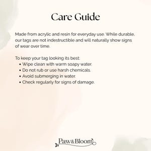 May include: A white informational card titled Care Guide with black text detailing maintenance for acrylic and resin tags. Instructions include wiping with warm soapy water, avoiding harsh chemicals, not submerging, and checking for damage. Paw&Bloom logo at bottom.