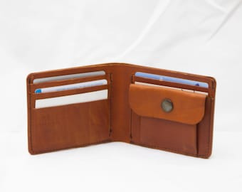 Puede incluir: Una cartera de cuero marrón con múltiples ranuras para tarjetas y un pequeño bolsillo. La cartera está abierta y el interior es visible.
