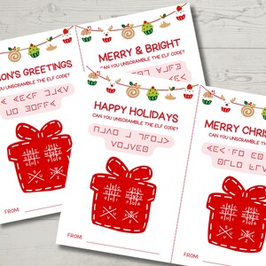 Może przedstawiać: Trzy kartki świąteczne z ilustracjami czerwonych pudełek z prezentami i napisami "Season's Greetings", "Merry & Bright", "Happy Holidays" i "Merry Christmas". Każda karta zawiera kod do rozszyfrowania i linię "From:"