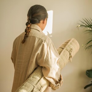 Back view of person carrying rolled hemp yoga mat using natural fiber shoulder strap. Great for on-the-go yoga and eco-travel