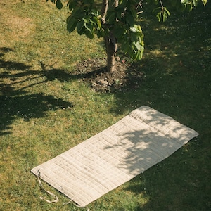 Unrolled hemp yoga mat on green grass, showing sturdy organic fabric and durable build. Ideal for eco-minded yogis seeking natural, non-slip mats for both indoor and outdoor practice