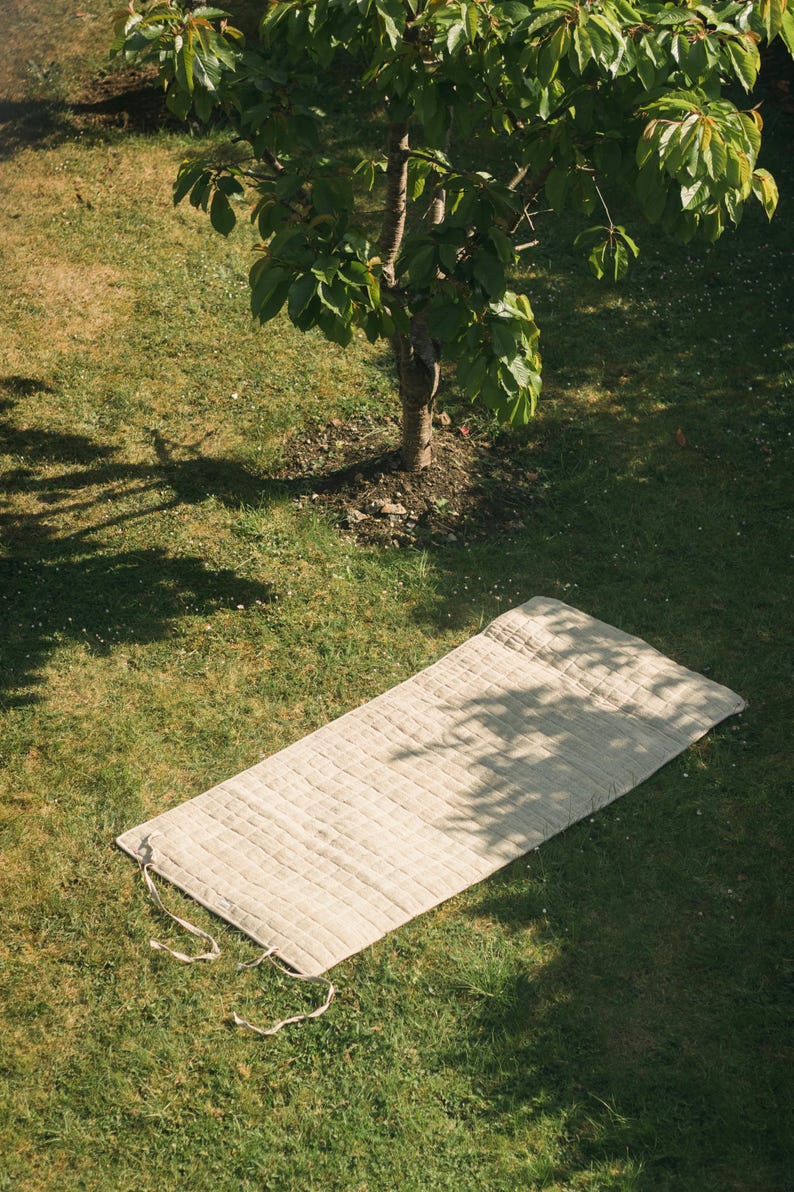 Unrolled hemp yoga mat on green grass, showing sturdy organic fabric and durable build. Ideal for eco-minded yogis seeking natural, non-slip mats for both indoor and outdoor practice