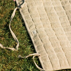 Unrolled hemp yoga mat on green grass, showing sturdy organic fabric and durable build. Ideal for eco-minded yogis seeking natural, non-slip mats for both indoor and outdoor practice.