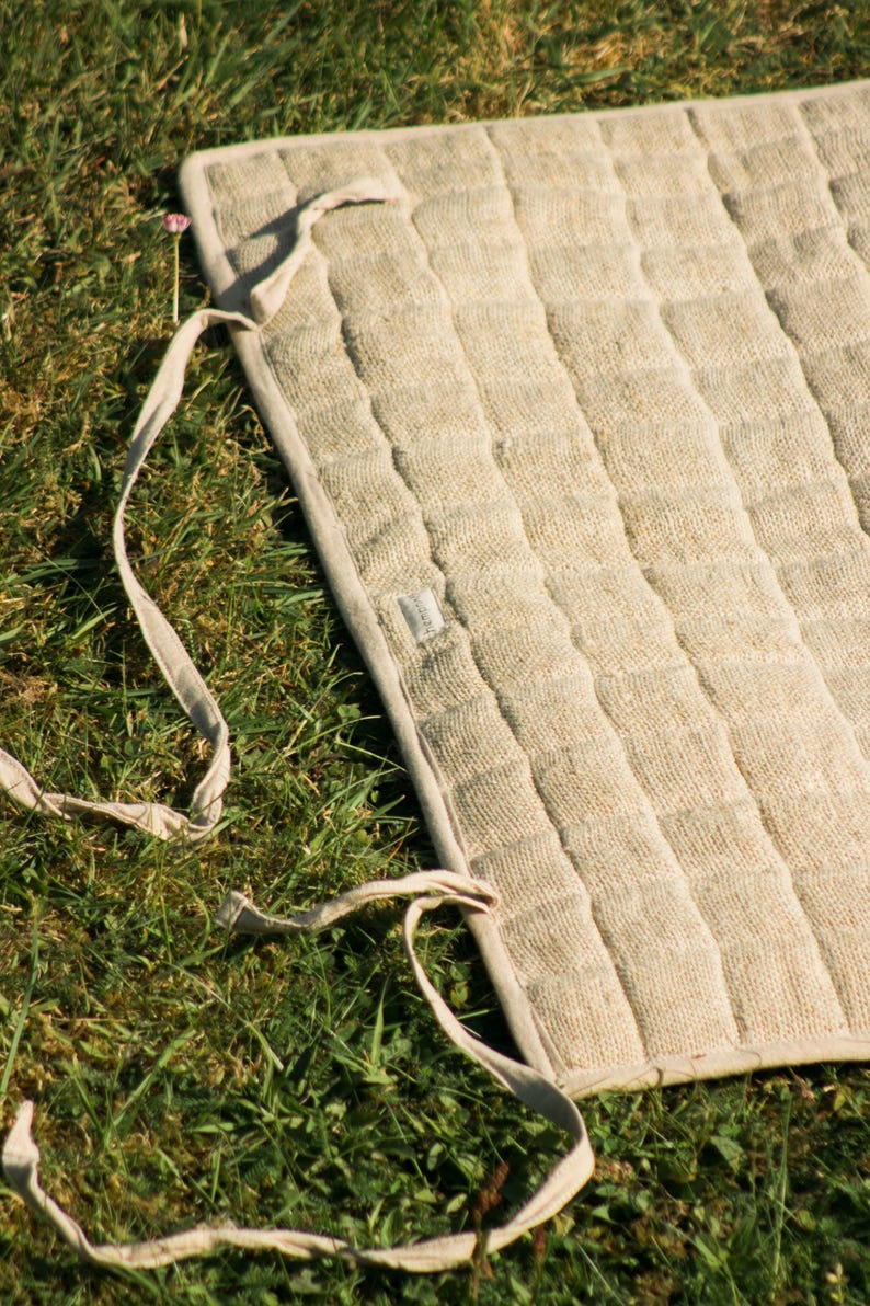 Unrolled hemp yoga mat on green grass, showing sturdy organic fabric and durable build. Ideal for eco-minded yogis seeking natural, non-slip mats for both indoor and outdoor practice.