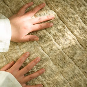 close up of the natural yoga mat with hands placed on it
