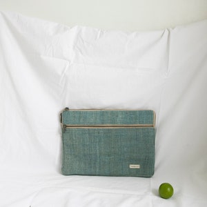 Eco-friendly hemp laptop sleeve in light blue, designed to fit 13-inch and 15-inch laptops. Features a minimalist, sustainable design with two spacious compartments for accessories.