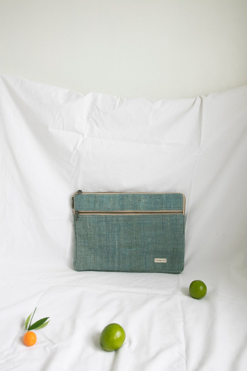 Eco-friendly hemp laptop sleeve in light blue, designed to fit 13-inch and 15-inch laptops. Features a minimalist, sustainable design with two spacious compartments for accessories.