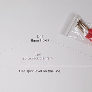 May include: Diagram showing how to install a 5 jar spice rack. It includes instructions to drill 6mm holes and use a spirit level to ensure the rack is level. The image also shows a bag of screws and wall anchors.