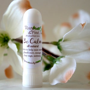 May include: White aromatherapy roller bottle with the text "Rugosa & Pine, Aromatherapy Be Calm all natural" and a list of ingredients: "ghandi root, orange, clary sage, nutmeg".