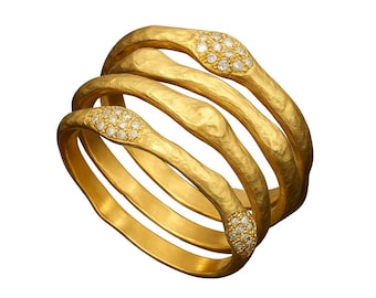 Può includere: Un anello a più fasce realizzato in oro giallo con una finitura martellata e testurizzata. Il design presenta tre fasce interconnesse, di cui due impreziosite da piccole pietre rotonde e chiare incastonate a grappolo sulla superficie.