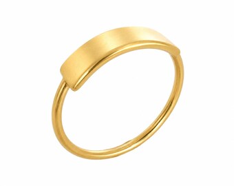 May include: A gold ring featuring a smooth, curved rectangular bar element centred on a thin, circular band. The metal has a consistent yellow gold tone with a polished finish, creating a clean and simple design that highlights the bar detail.