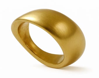 Puede incluir: Un anillo dorado con un diseño suave y redondeado. El anillo tiene una textura de metal cepillado y una banda ancha. El anillo está sobre un fondo blanco, resaltando su forma y color. El anillo es una pieza de joyería.