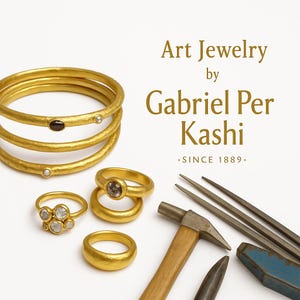 May include: Gold jewelry set against a white background. The image features multiple rings, including a stack of three gold bangles, and rings with gemstones. The text reads "Art Jewelry by Gabriel Per Kashi .SINCE 1889."