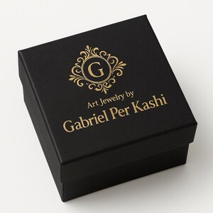 May include: A black jewelry box with gold lettering and a decorative emblem. The box reads "Art Jewelry by Gabriel Per Kashi". The emblem features the letter "G" inside a circular design with ornate flourishes.