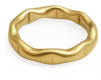 May include: A gold-colored ring with an irregular, wavy design. The ring has a smooth, matte finish and is marked with the number "916". The ring's shape is not perfectly circular, adding to its unique aesthetic. A piece of jewelry.