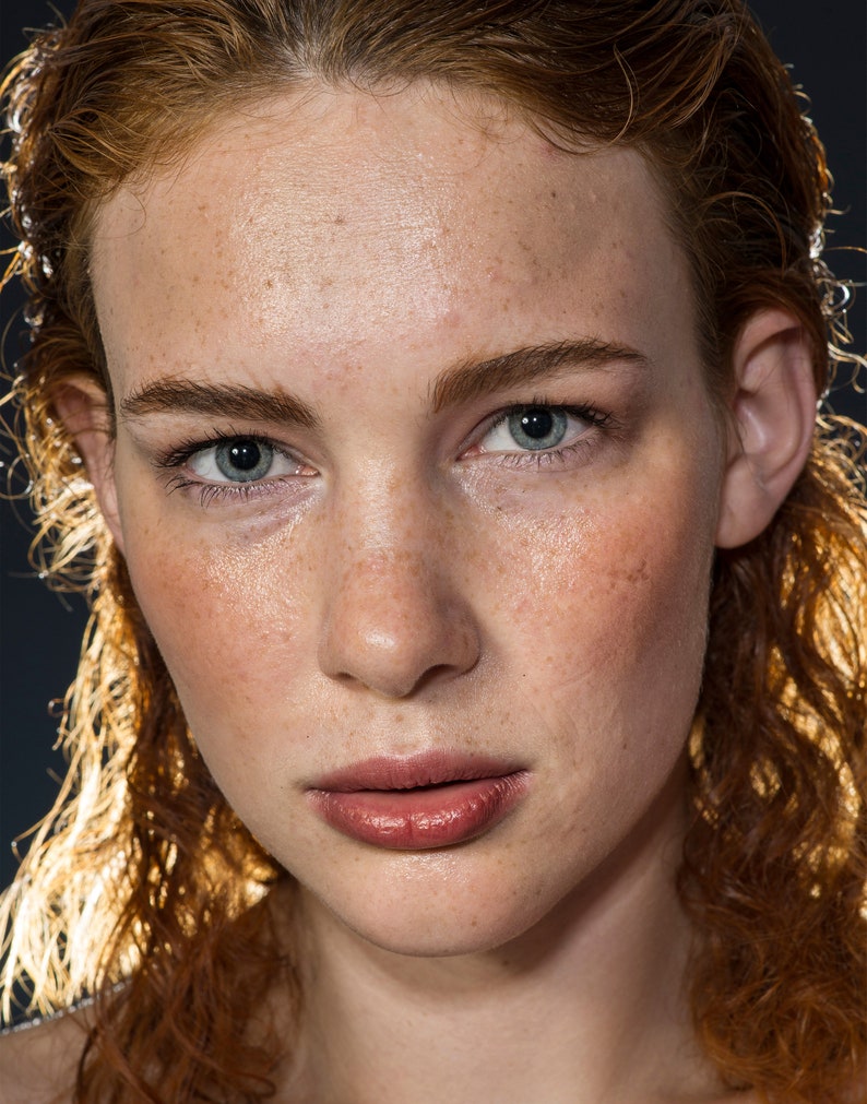 Peut inclure: Portrait rapproch&eacute; d'une femme aux cheveux roux et aux taches de rousseur. Elle a une expression neutre, les l&egrave;vres l&eacute;g&egrave;rement entrouvertes. Sa peau est claire et ses yeux sont bleus.