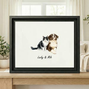 Może przedstawiać: Oprawiony wydruk akwarelowy przedstawiający czarno-białego kota i brązowo-białego psa. Kot siedzi, a pies leży. Wydruk jest w czarnej ramie, a pod zwierzętami widnieją napisy "Lucky & Milo".
