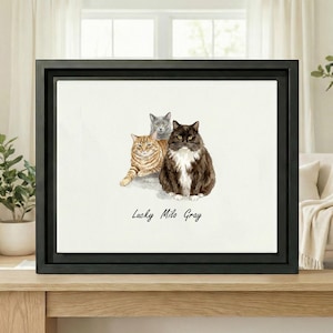 Puede incluir: Una impresión en acuarela enmarcada con tres gatos: un gato marrón y blanco, un gato atigrado y un gato gris. El texto "Lucky Milo Gray" está escrito debajo.