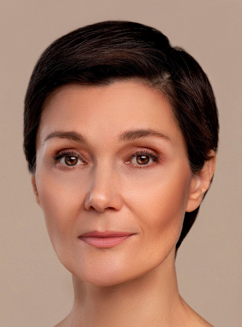 Peut inclure: Portrait rapproch&eacute; d'une femme aux cheveux courts et bruns fonc&eacute;s. Elle a une expression neutre sur le visage et regarde directement la cam&eacute;ra. Sa peau est lisse et ses yeux sont bruns.