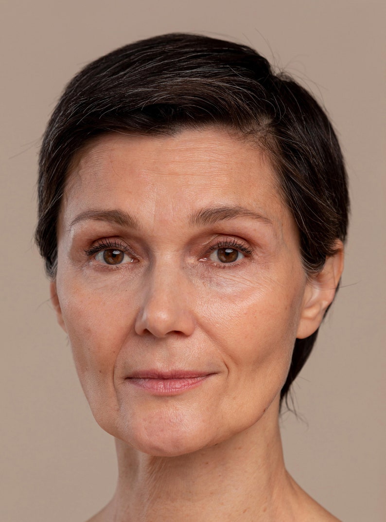 Peut inclure: Portrait rapproch&eacute; d'une femme aux cheveux courts et fonc&eacute;s. Elle a une expression neutre sur le visage, ses yeux regardant directement la cam&eacute;ra.
