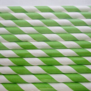 May include: A close-up of a stack of green and white striped paper straws. The straws are arranged in a neat, overlapping pattern.