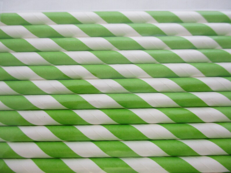May include: A close-up of a stack of green and white striped paper straws. The straws are arranged in a neat, overlapping pattern.