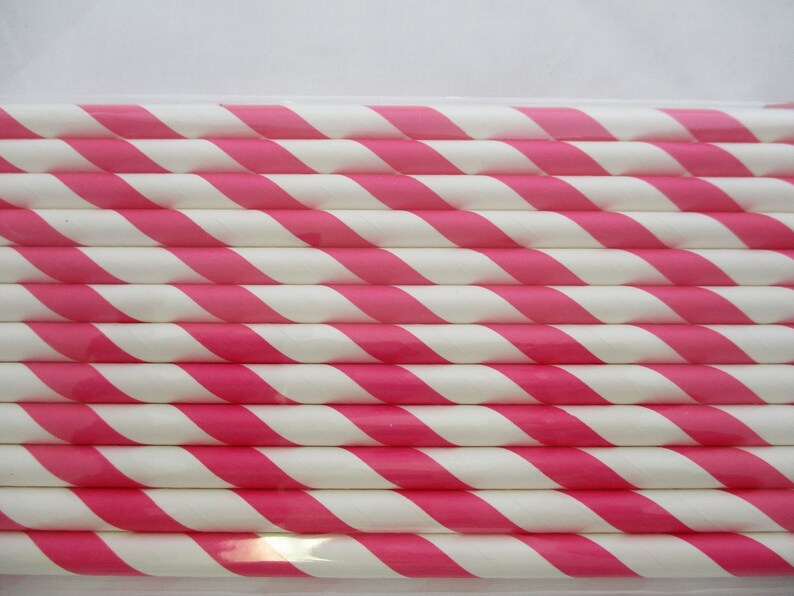 May include: A close-up of a bundle of pink and white striped paper straws. The straws are arranged in a neat stack, with the pink stripes running diagonally across the straws.