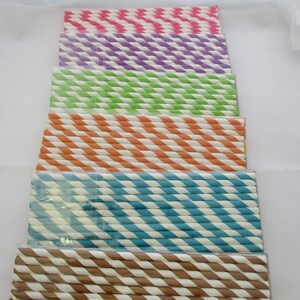 May include: A stack of colorful striped paper straws in pink, purple, green, orange, blue, and brown. The straws are arranged in a vertical stack, with the pink straws at the top and the brown straws at the bottom.