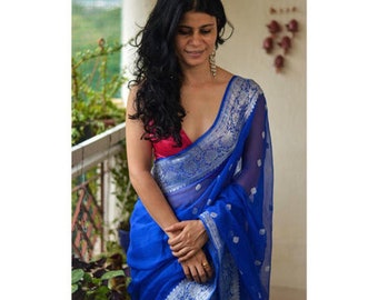 May include: A woman wearing a blue and silver saree with a pink blouse. The saree has a silver border and a floral pattern.