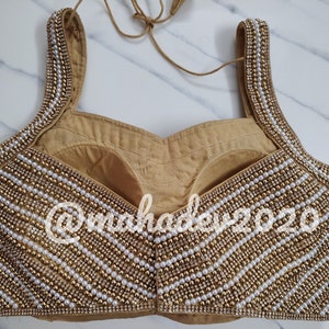 Pu&ograve; includere: Un choli dorato e bianco con perline e scollatura a cuore. Il choli &egrave; decorato con file di perle e perline dorate.