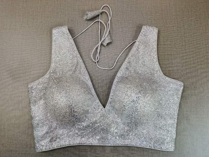 May include: A silver sequined sleeveless blouse with a deep V-neckline.