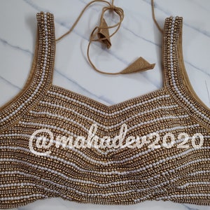 Pu&ograve; includere: Un choli con perline dorate e bianche, con scollo quadrato e spalline sottili. Il choli &egrave; decorato con file di perle e perline dorate. Il choli &egrave; un capo tradizionale indiano indossato dalle donne.