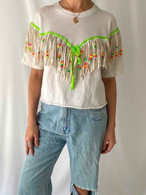A genuinely reworked 90s vintage crop tee with fringes and beading — the kind of one-of-a-kind piece you'd find at a festival, not a factory.