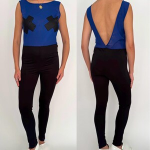 Peut inclure: Une combinaison bleue sans manches avec des patchs en forme de X noirs sur le devant et un dos bas. La combinaison a un pantalon noir.