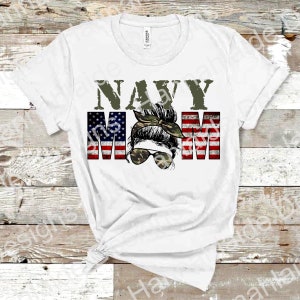 May include: White t-shirt with the text "NAVY MOM" in green letters. The "MOM" is made up of American flag stripes with a woman's face in the middle wearing a camouflage bandana and sunglasses.