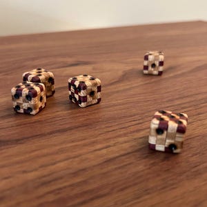 May include: Five wooden dice with black dots and a checkered pattern in shades of brown and maroon.