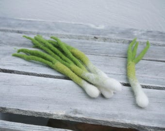 Può includere: Cipolline in feltro fatte a mano con estremità a bulbo bianco, disposte su una superficie di legno invecchiato. Le cime verdi passano a un verde-giallo più chiaro. Un cipollotto è isolato, mostrando i dettagli dell'artigianato.