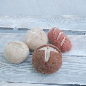 Könnte beinhalten: Vier Filzbrötchen in verschiedenen Farben und Formen. Zwei sind beige, eines ist braun und eines ist rotbraun.