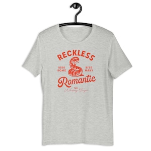 May include: Grey t-shirt with a red snake graphic and the text "Reckless Romantic The Whiskey Ginger" printed on the front.