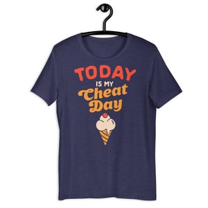 May include: Navy blue t-shirt with the text "TODAY IS MY CHEAT DAY" in red and orange lettering. An ice cream cone with a cherry on top is below the text.