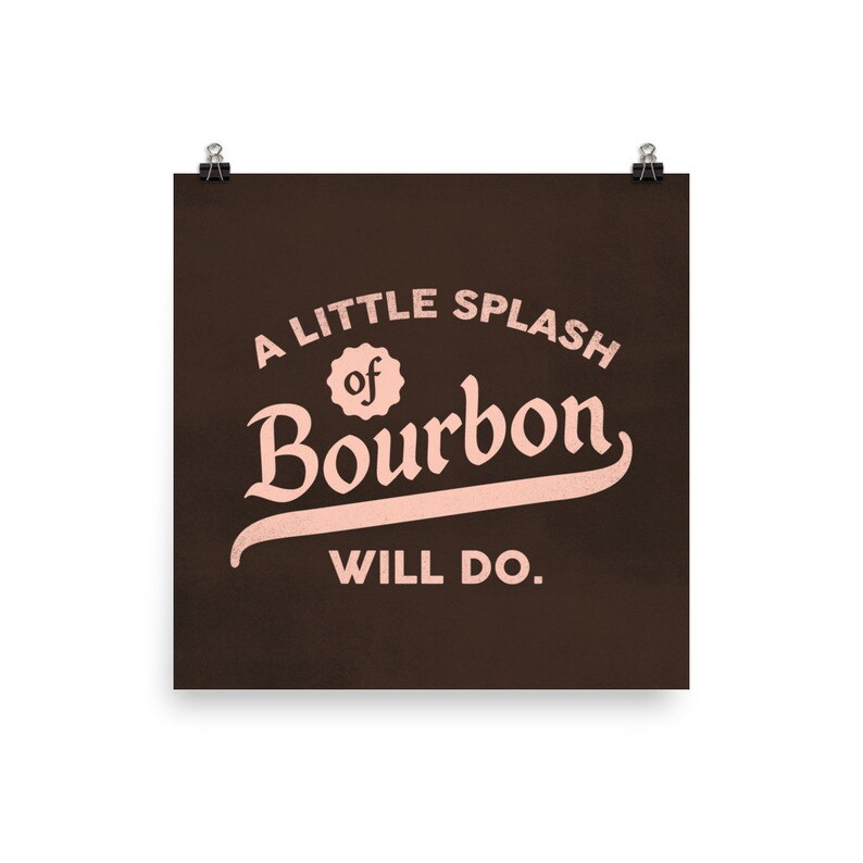 May include: A brown poster with the text "A little splash of Bourbon will do." in pink lettering.