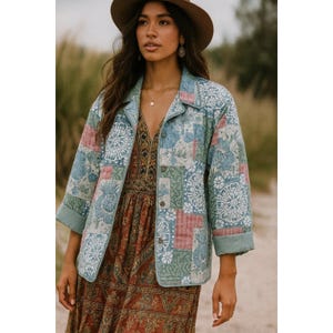 May include: A patchwork jacket with a floral pattern in shades of blue, pink, and green. The jacket has a collared neckline and button-up front. The sleeves are cuffed. The jacket is worn over a patterned dress.