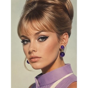 May include: A woman with blonde hair styled in a bouffant and bangs, wearing purple drop earrings. Her makeup includes dramatic black eyeliner and a light purple top.