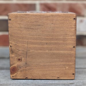 May include: A wooden box with a natural brown stain. The box is made of solid wood and has a simple, rustic design.