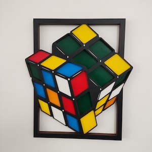 Può includere: Una scultura in legno 3D di un cubo di Rubik, dipinto nei colori classici rosso, blu, verde, giallo, arancione e bianco. Il cubo è inclinato e sembra ruotare, creando un effetto dinamico e astratto.