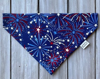 May include: A blue bandana with a white and red fireworks pattern. The bandana has a small white tag with the text "Pawty's Ruffwear" on it.